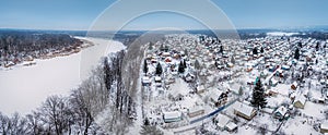Russian dacha village near river and forest in winter, aerial view