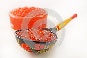 Traditional russian food. Red caviar in Wooden spoon painted in traditional style Khokhloma.