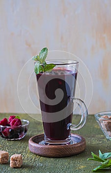 Traditional Russian hot or cold drink, blueberry jelly or kissel in a glass mug on a green concrete background