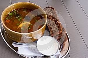 Traditional Russian meat soup solyanka in a bowl, with sour cream and black bread. Krasnaya Polyana, Sochi, Russia