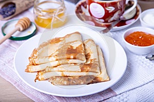 Traditional Russian pancakes with honey, sour cream and jam.