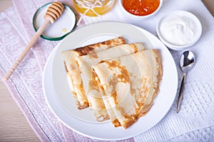 Traditional Russian pancakes with honey, sour cream and jam.