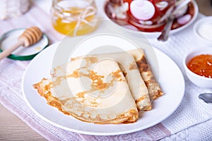 Traditional Russian pancakes with honey, sour cream and jam.