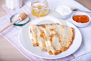 Traditional Russian pancakes with honey, sour cream and jam.