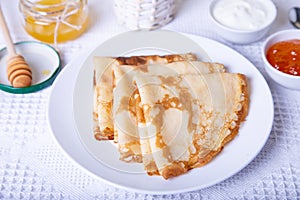 Traditional Russian pancakes with honey, sour cream and jam.