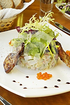 Traditional Russian salad with grilled quail and red caviar