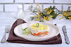 Traditional Russian salad Mimosa with boiled pink salmon, carrots, onions and eggs on a gray concrete background