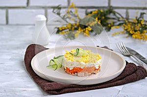 Traditional Russian salad Mimosa with boiled pink salmon, carrots, onions and eggs on a gray concrete background