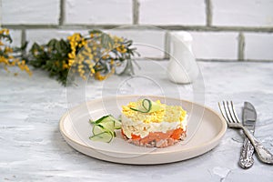 Traditional Russian salad Mimosa with boiled pink salmon, carrots, onions and eggs on a gray concrete background