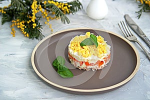 Traditional Russian salad Mimosa with boiled pink salmon, carrots, onions and eggs on a gray concrete background