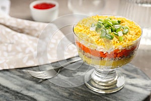Traditional russian salad Mimosa in bowl on grey board, closeup. Space for text