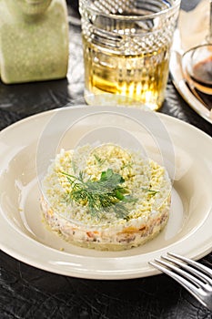 Traditional Russian salad Mimosa with freah dill on top served on the table