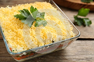 Traditional russian salad Mimosa served on wooden table, closeup