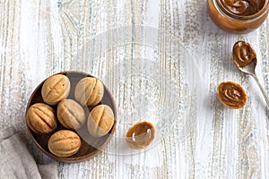 Traditional Russian  shortbread nuts with boiled condensed milk, sprinkled with powdered sugar in a wooden bowl on a wooden