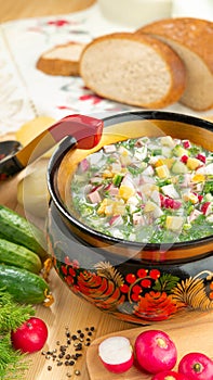 Traditional Russian summer cold okroshka soup with kefir in a bowl on a wood table. View from above. Khokhloma-style wooden dishes