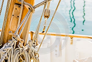 Traditional sailing boat deck, rigging tied nautical ropes on cleats on wooden mast