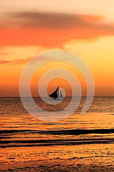 Traditional sailing boat in silhouette with a tropical sunset