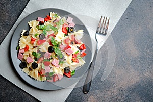 Traditional salad with pasta farfalle, ham, pepper and herbs