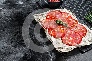 Traditional salami chorizo sausage. Black background. Top view. Space for text