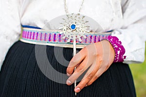 Traditional Saraguro women's silver jewelry in a woman's hand with a blue stone on its center photo