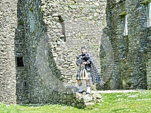 Traditional scottish bagpiper at ruins of Kilchurn castle