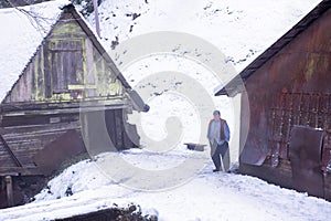 Traditional senior blacksmith in front of watermill