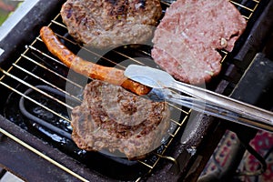 Traditional serbian barbecue rostilj  homemade sausages and burgers. Preparing a barbecue on a grill, Barbecue tong,outdoor roas