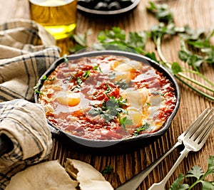 Traditional shakshuka dish served in a cast iron pan on wooden table