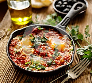 Traditional shakshuka dish served in a cast iron pan on wooden table