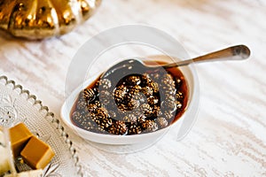 Traditional Siberian dessert - Jam of young pine cones. Selective focus. Jam of fir cones in a plate on the table