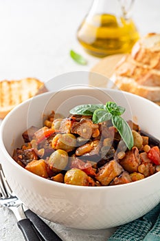 Traditional sicilian eggplant dish Caponata in bowl on concrete background