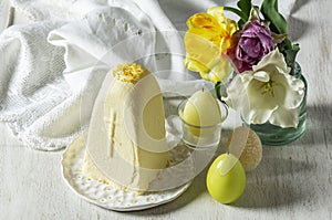 Traditional Slavic Easter dish made from cottage cheese - Paskha, a bouquet of tulips and candles on a light background.