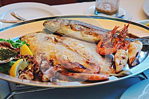 Traditional slovenian cuisine, mixed grilled fish and seafood with garlic oil. Selective focus