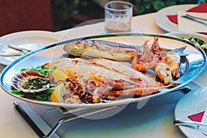 Traditional slovenian cuisine, mixed grilled fish and seafood with garlic oil. Selective focus