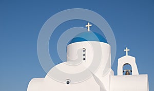 Traditional small christian orthodox church with belfry white and blue dome against cloudy sky.