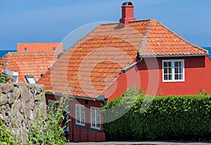 a traditional small,red,danish framehouse in summer in Bornholm with blue sky