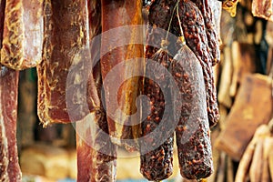 Traditional smoked pork meat products hanging in smokehouse for sale