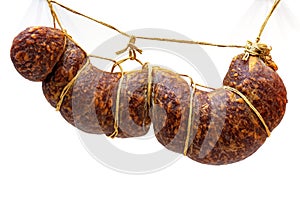 Traditional smoked sausage hanging on ropes on white background