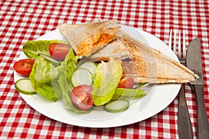 A traditional snack of a toasted sandwich with salad