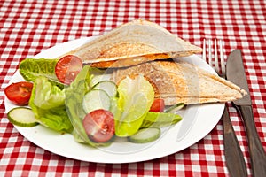 A traditional snack of a toasted sandwich with salad