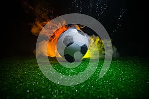 Traditional soccer ball on soccer field. Close up view of soccer ball (football) on green grass with dark toned foggy background.