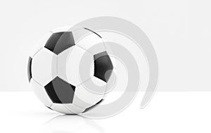 Traditional soccer ball with stitching on white surface with reflection and light grey background and copyspace