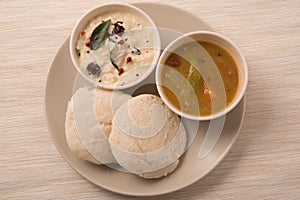 Traditional south indian food, idli or idly with sambar and white coconut coconut in white plate.