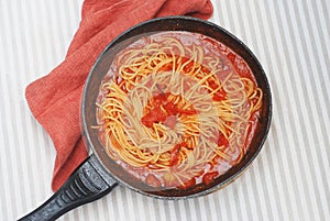 Traditional Spaghetti with Tomatoe Sauce Italy in Iron Pan with Orange Napkin on Table. Dinner. Top view.
