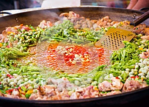 Traditional spanish chicken paella preparation on big pan, outdoors food market