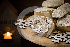 Traditional Spanish Christmas cookies polvorones, nevaditos and mantecados on a wood cake stand, lit candle, photo