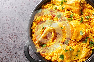 Traditional Spanish dish Conejo con arroz that combines rice with rabbit meat closeup in the pan. Horizontal top view photo