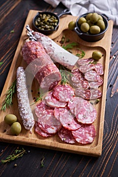 Traditional Spanish fuet salami sausage on wooden cutting board at domestic kitchen