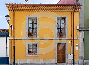Traditional Spanish house. Old building restored, facade painted in yellow. Windows and balcony framed with grey stone. Wooden