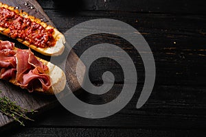 Traditional Spanish Jamon Serrano ham, on black wooden table background, with copy space for text